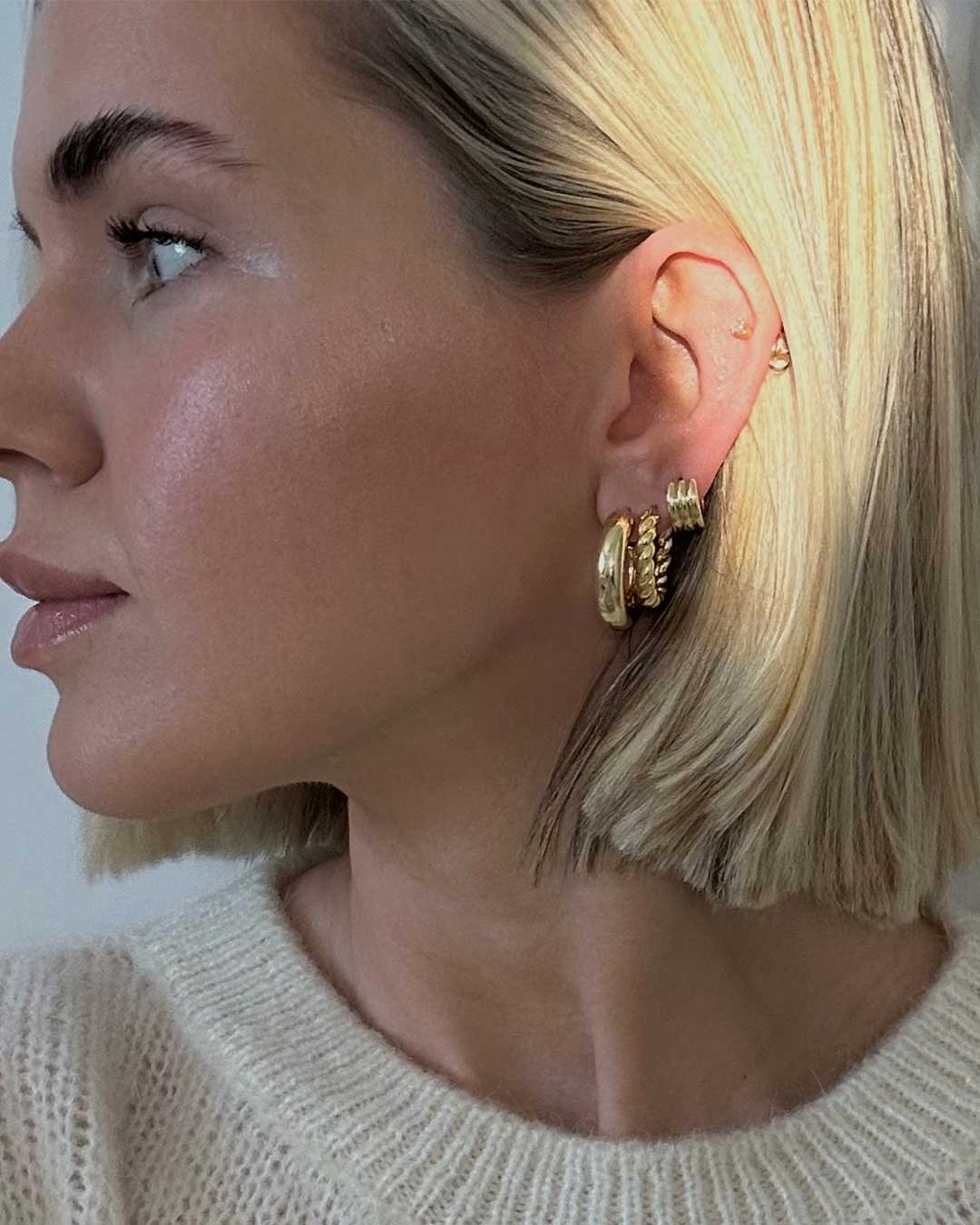 Woman wearing gold plated hoops and huggies
