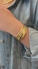 a wrist stacked with gold bracelets